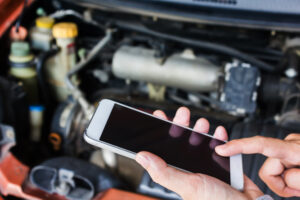 Man calling mechanic over the hood of broken car